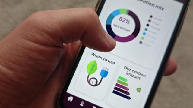Hand holding a phone which displays an energy system dashboard