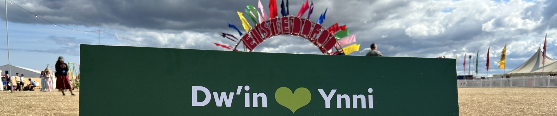 Sign in Welsh reading 'I love renewable energy for Wales' and with a Trydan logo. in the background is an Eisteddfod-themed archway on the site of the Eisteddfod.