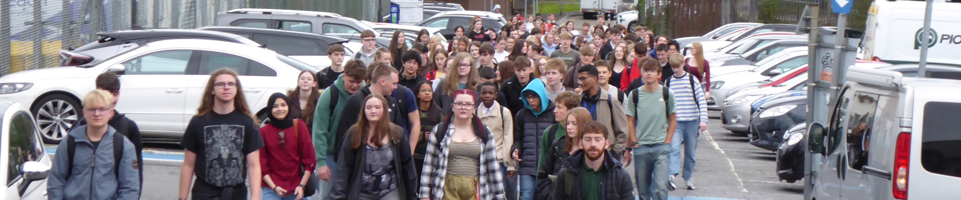 large group of young people walking through a car park