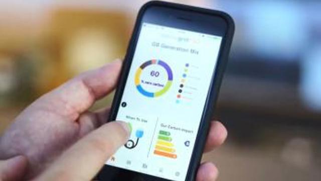 Picture of someone holding their smartphone checking the ESO's Carbon-intensity dashboard. 